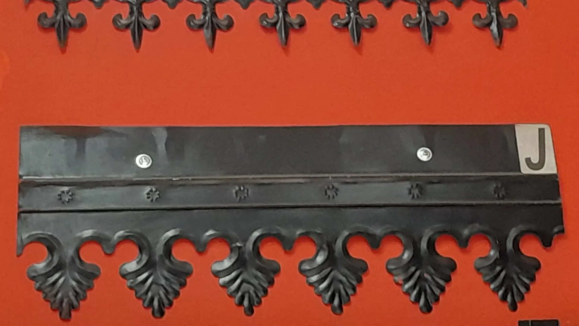 Cenefas de chapa estampadas con relieve, en negro: flor de lis arriba y piña abajo