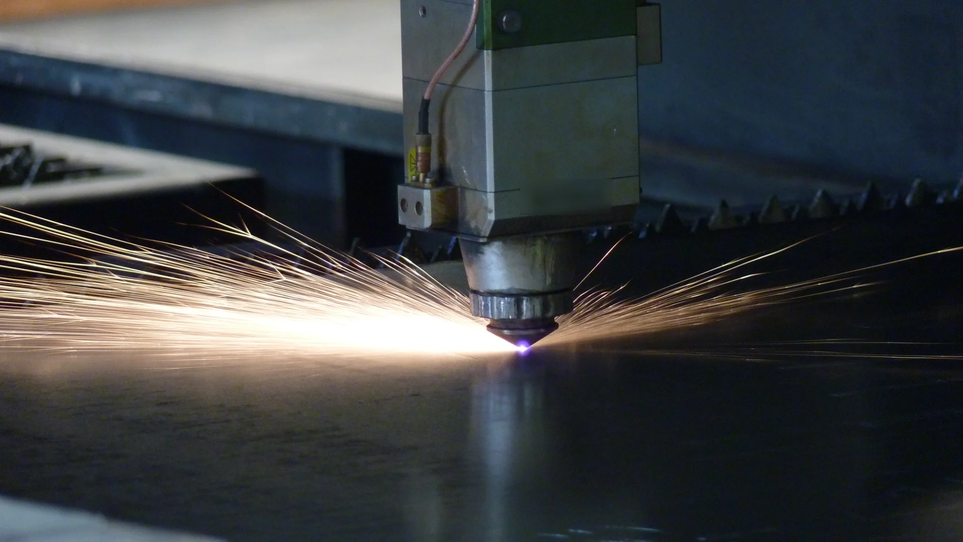 Cabezal del láser CNC cortando chapa con un abanico de chispas