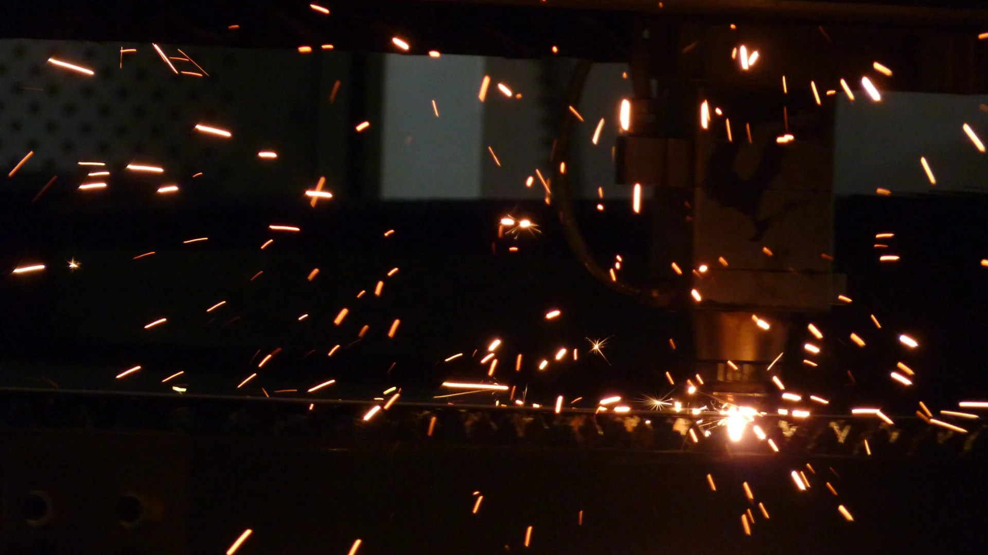 Láser CNC cortando en la planta, con chispas en la oscuridad