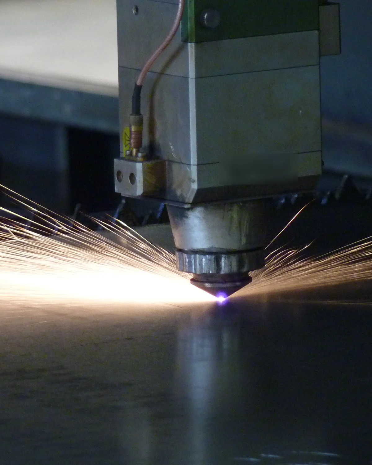 Cabezal del láser CNC cortando chapa con un abanico de chispas