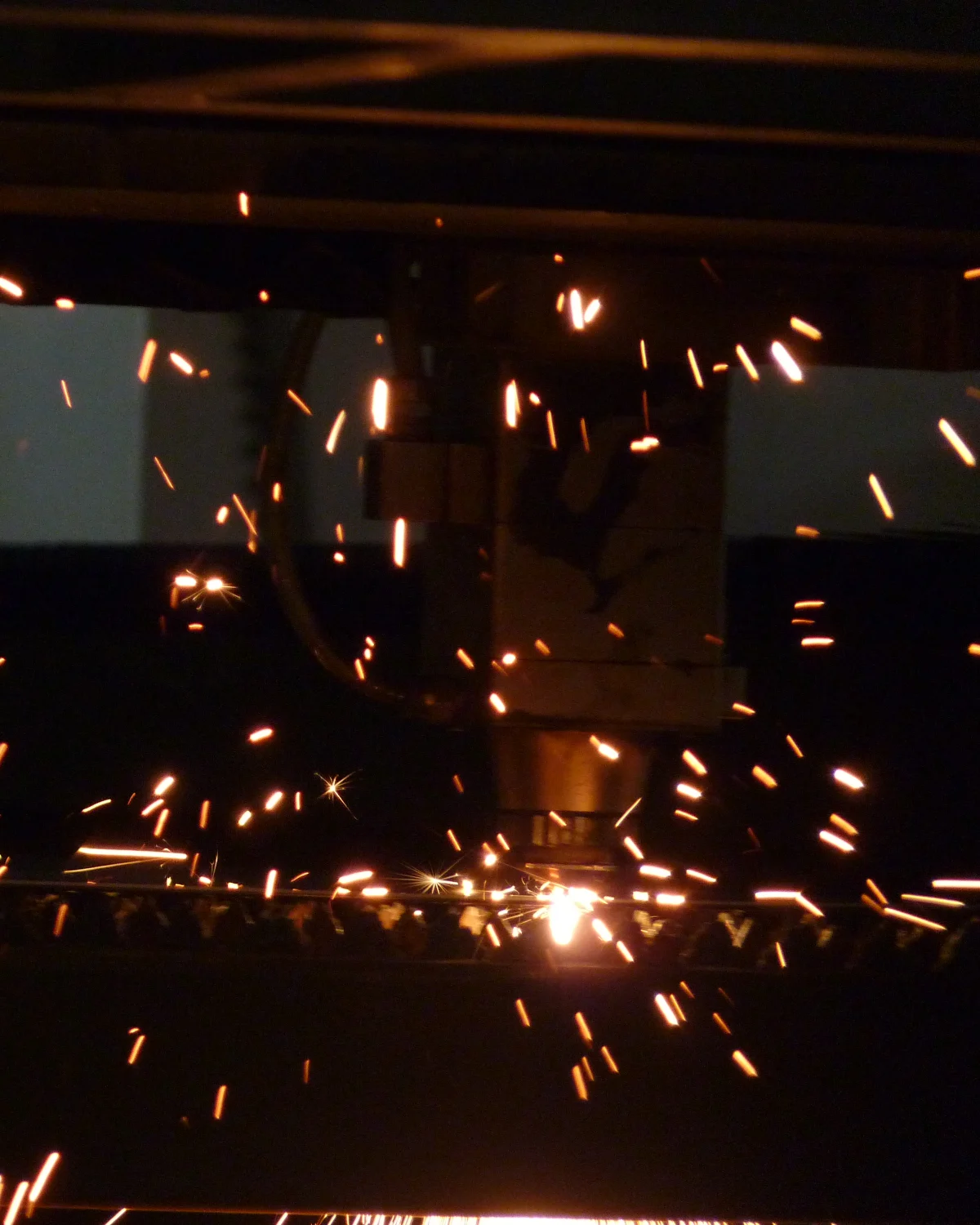 Láser CNC cortando en la planta, con chispas en la oscuridad