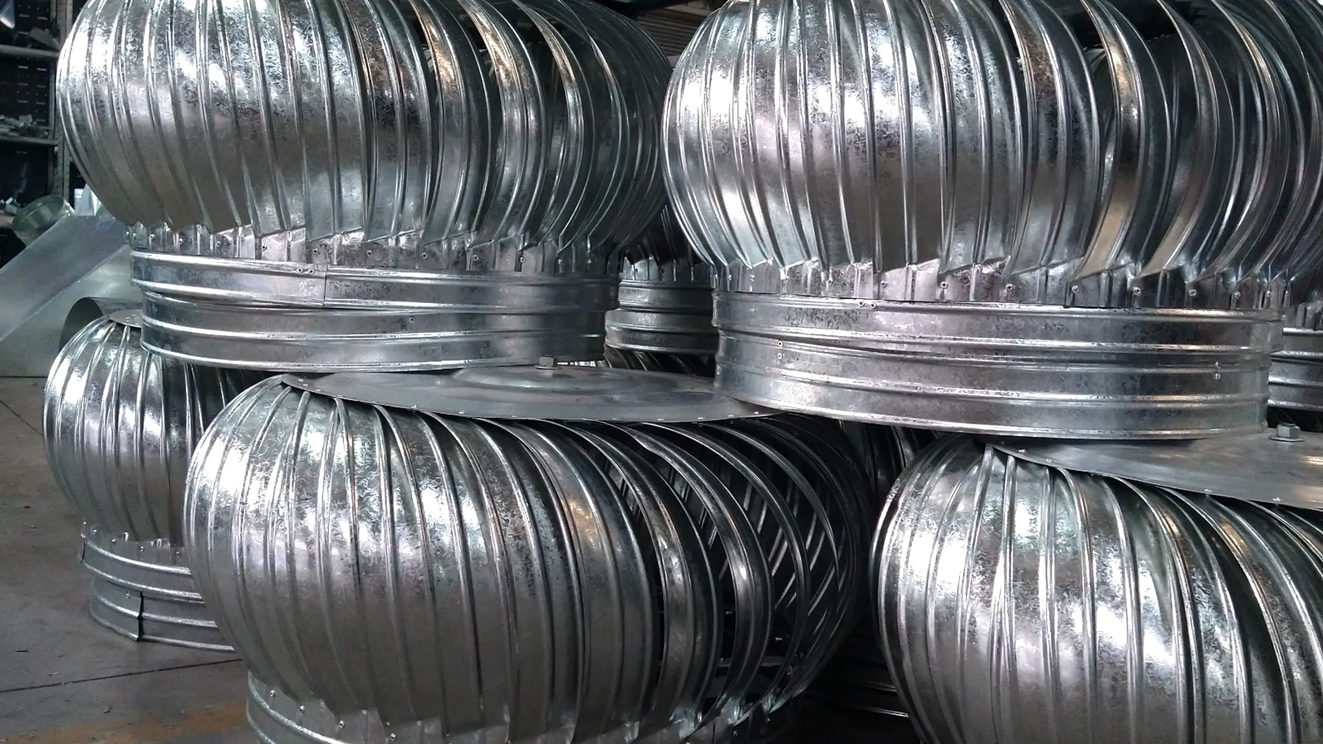 Sombreros eólicos de chapa galvanizada apilados en el taller